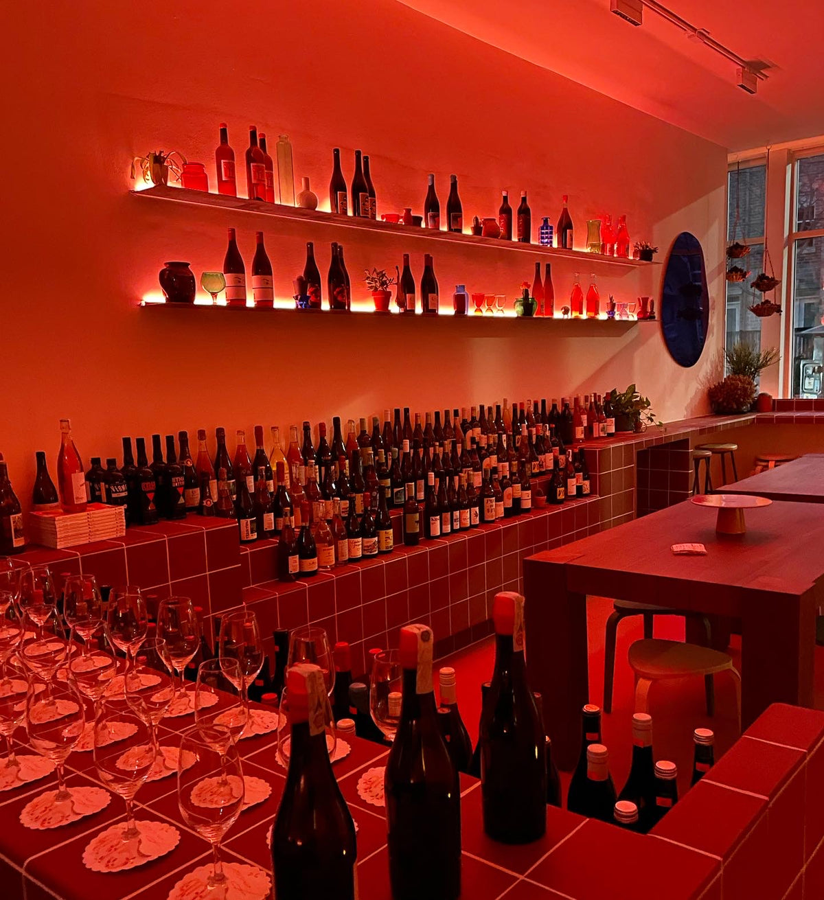 Warm red-lit wine shelves and bar inside Club Paris